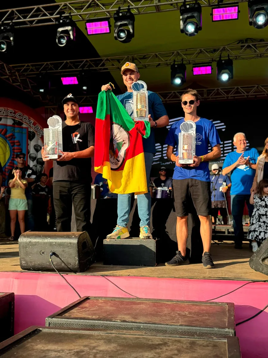 João Vitor Justo no lugar mais alto do pódio do Campeonato Brasileiro de Balonismo de 2024, segurando a bandeira do Rio Grande do Sul