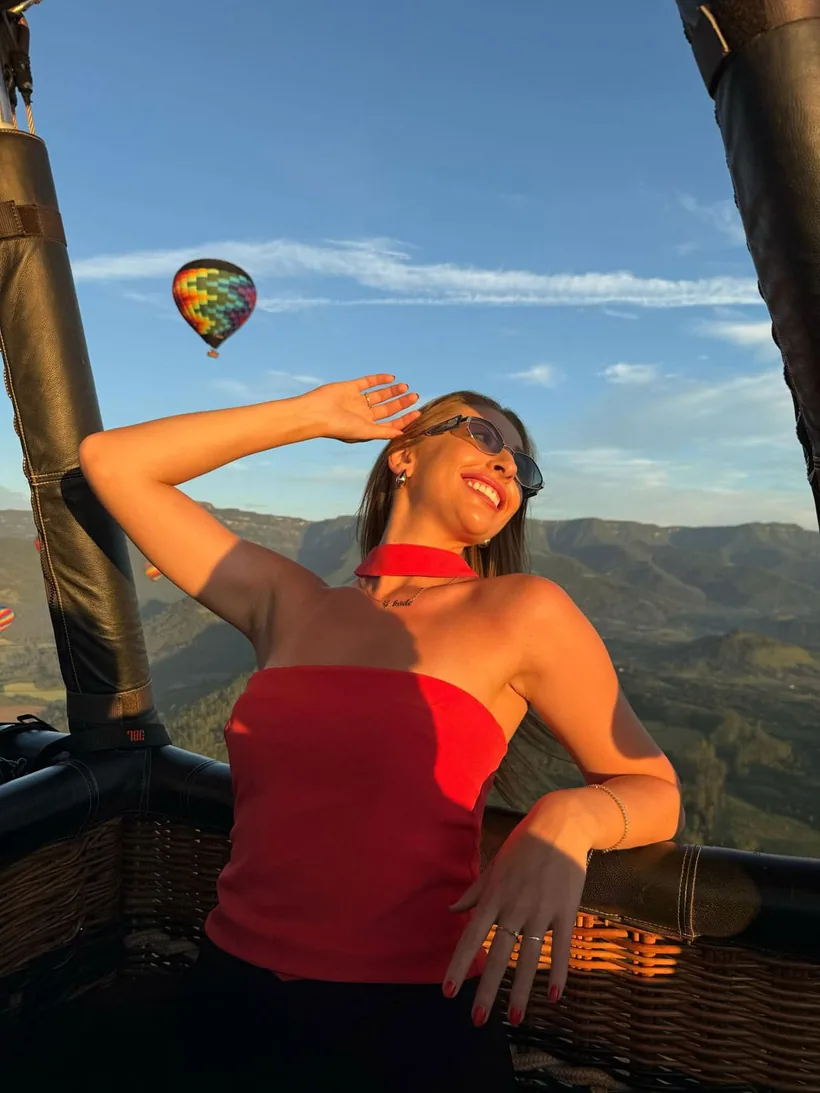 Passageira sorrindo no cesto do balão com outro balão e os cânions ao fundo